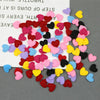 A colorful assortment of felt heart appliques in various shades of pink, red, yellow, purple, and blue scattered on a white s