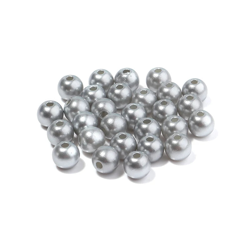 A pile of small, round silver imitation pearl beads for DIY jewelry making.