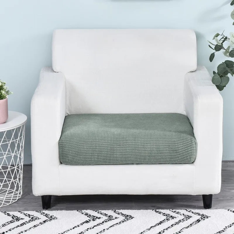 A white armchair with a green fleece seat cushion cover placed on a wooden floor.