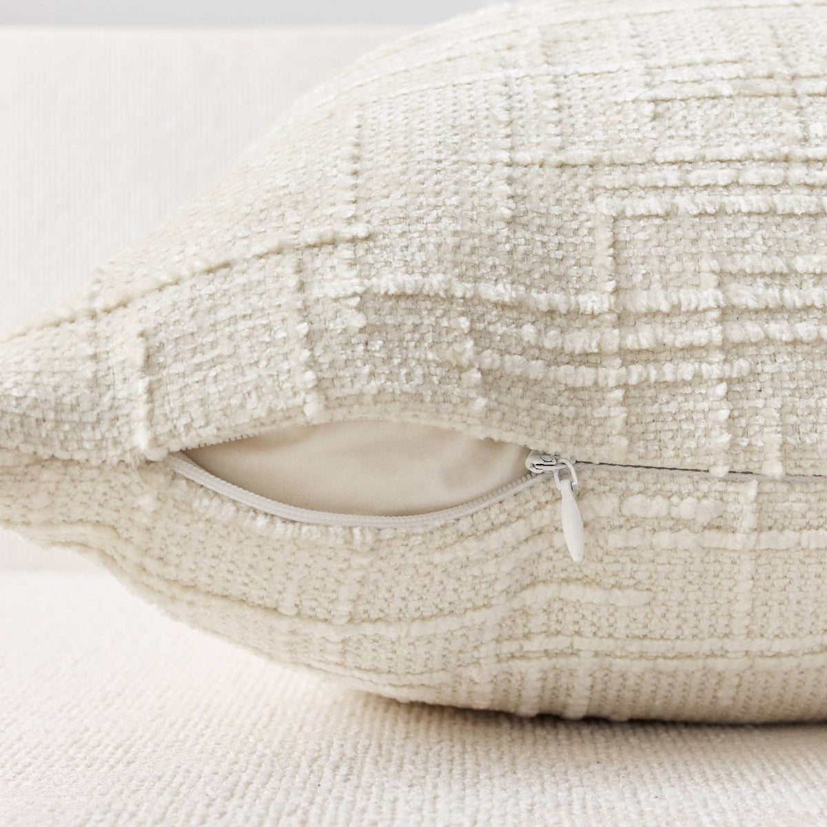 A cream-colored boucle texture throw pillow cover with a zippered opening.