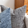 A close-up of a gray boucle texture throw pillow cover resting on a sofa.