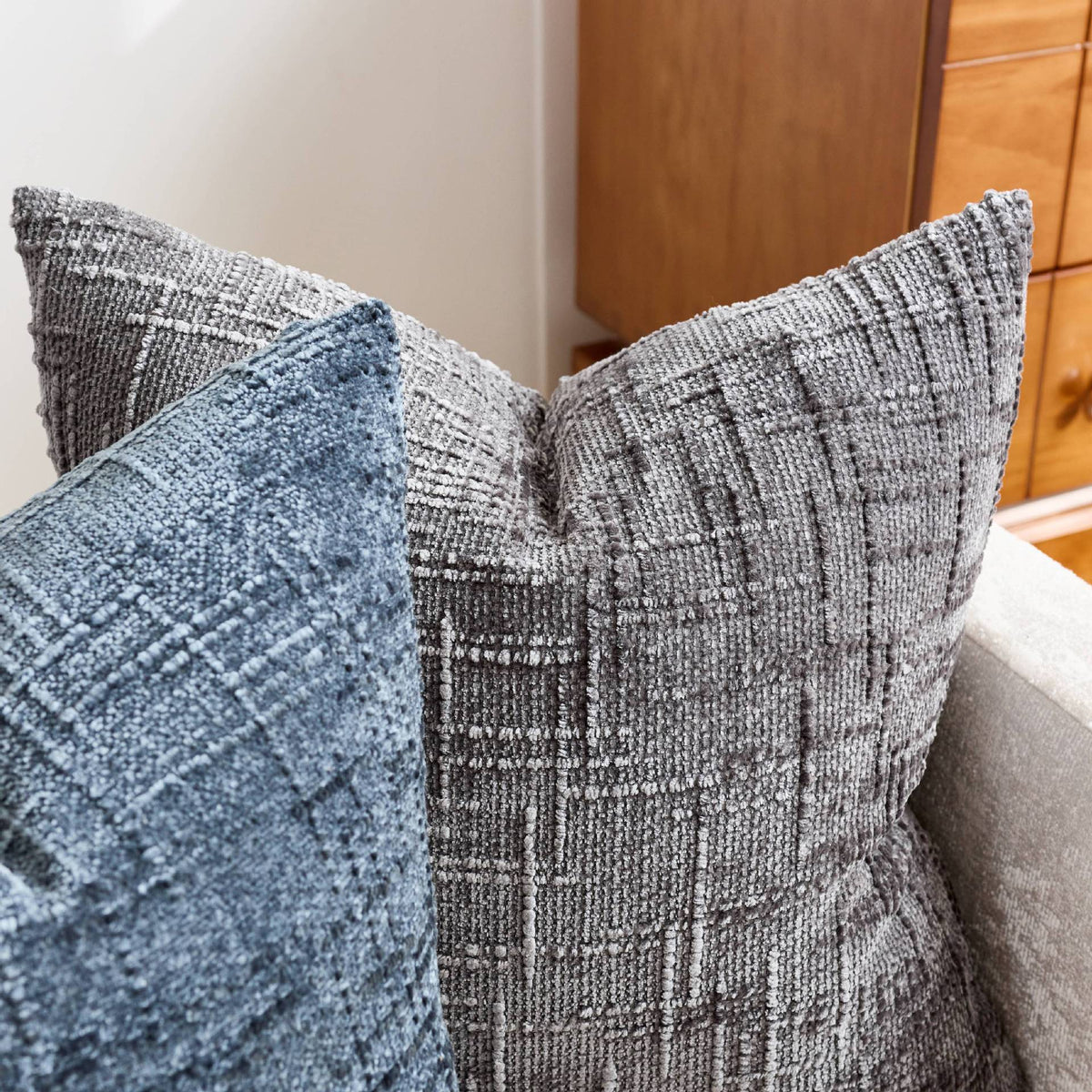 A close-up of a gray boucle texture throw pillow cover resting on a sofa.