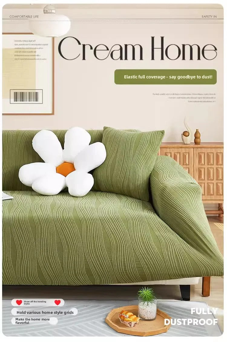 A green textured sofa cover with white floral accents is displayed on a light gray floor, emphasizing its elastic and dustpro
