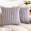 A pair of gray faux rabbit fur cushion covers resting on a light-colored sofa.