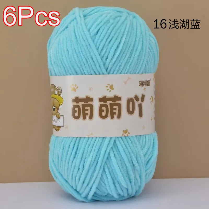 A skein of light blue soft bulky chenille yarn with a label featuring Chinese characters.