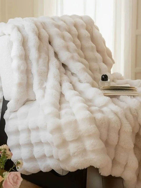 A fluffy white faux rabbit fleece throw blanket draped over a surface.