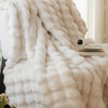 A fluffy white faux rabbit fur throw blanket draped over a surface.