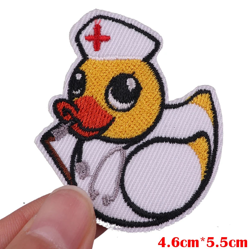 An embroidered cartoon patch of a yellow duck wearing a white cap and holding a stick.