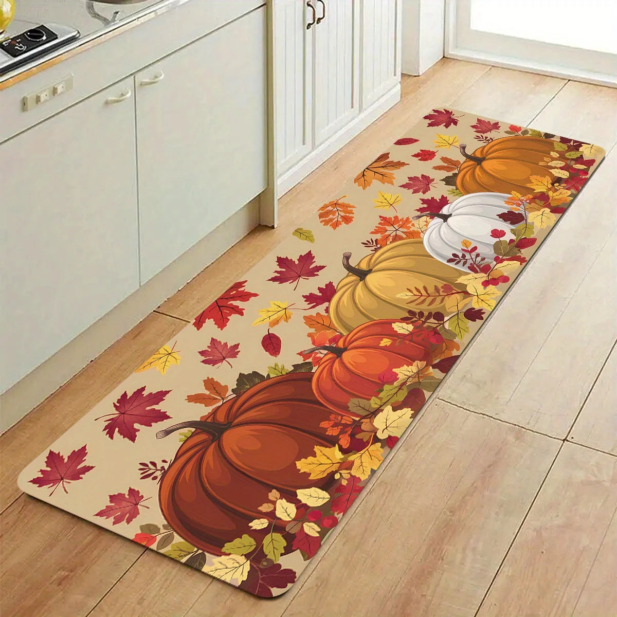 An area rug featuring an autumn harvest design with orange and yellow pumpkins and maple leaves.