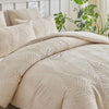 A beige embossed leaf duvet cover set displayed on a bed with green foliage in the background.