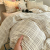 A close-up of a beige and white plaid duvet cover and pillow set on a bed.