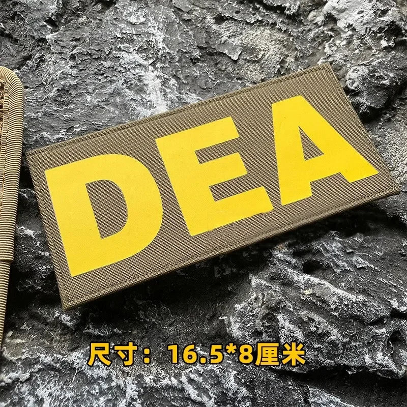 A yellow tactical hook and loop patch labeled DEA is placed on a dark, rough rock surface.