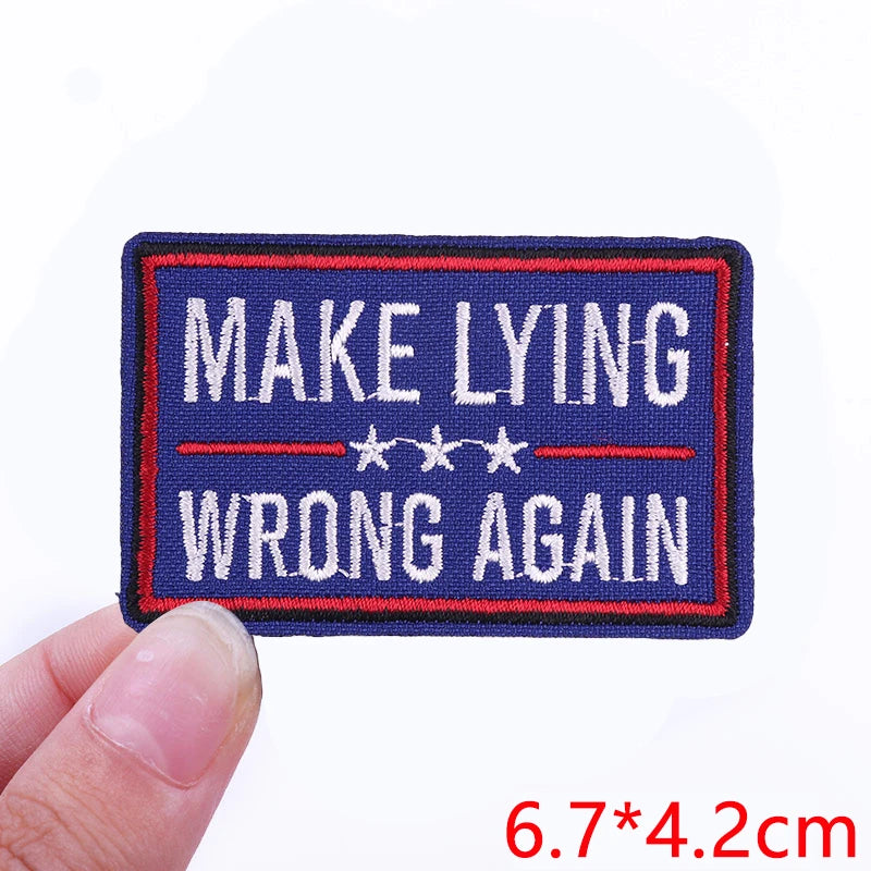 A dark blue embroidered patch with red and white text that reads MAKE LYING WRONG AGAIN