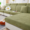 A light olive green leaf jacquard stretch sofa cover with a textured pattern displayed on a modern sofa.