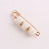 Gold-toned adjustable pearl brooch featuring small diamond accents.
