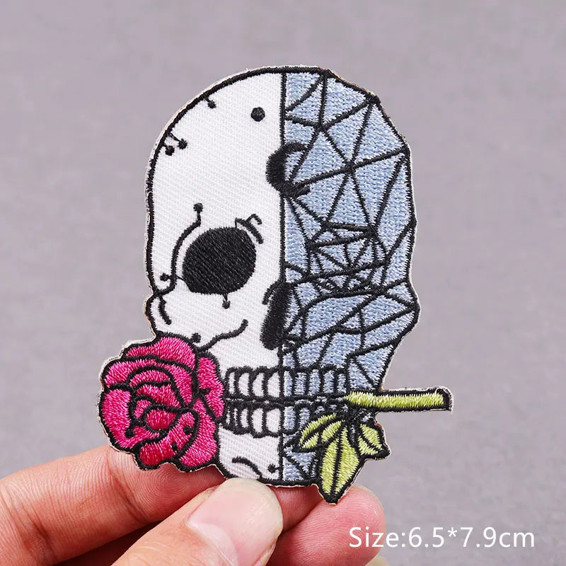 Embroidered skull patch featuring a pink rose and green leaves on a fabric background