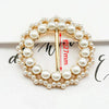 A gold-toned metal ring clip featuring a pearl border and a vertical pin, used for clothing or accessories.