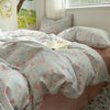A pink floral duvet set with light blue and white patterns is displayed on a bed next to a window.