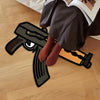 A dark gray gun-shaped rug is partially visible under a person's legs on a wooden floor.