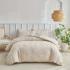 A beige embossed leaf duvet cover set displayed on a bed with a light wood headboard and woven lampshade.