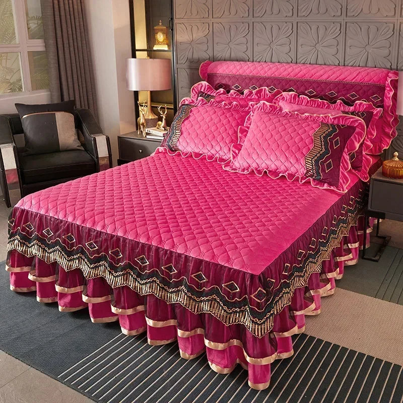 A vibrant pink quilted bed skirt with ruffled edges and gold trim is displayed on a bed.