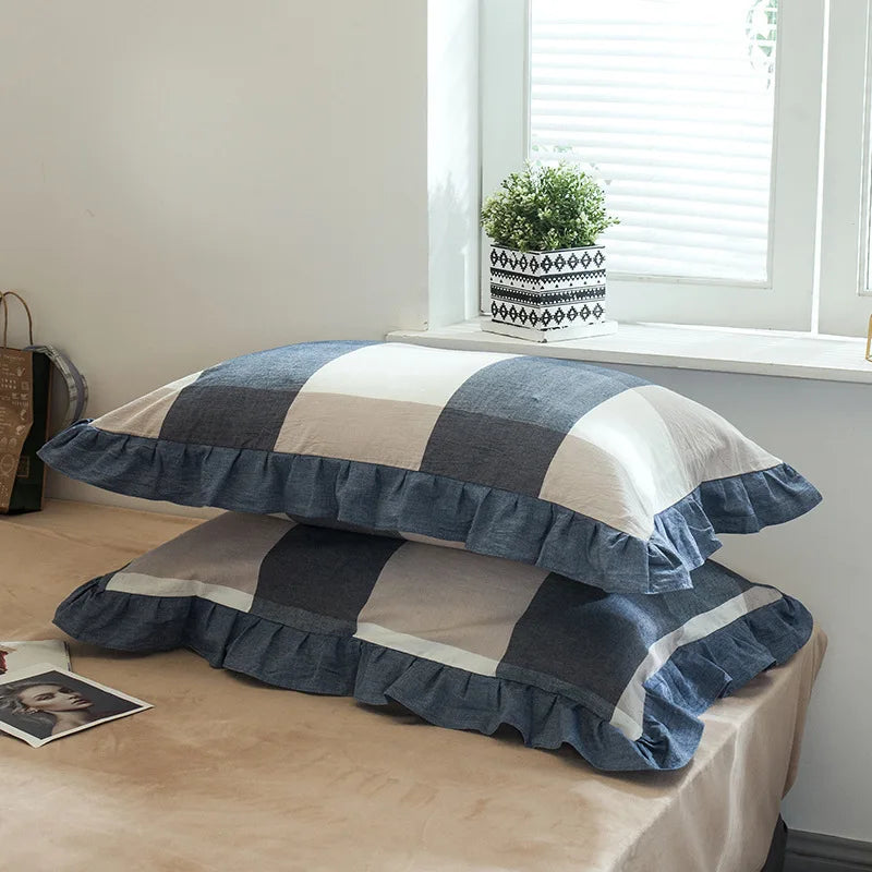A set of two soft plaid washed cotton pillowcases with ruffled edges in blue, gray, and beige tones.