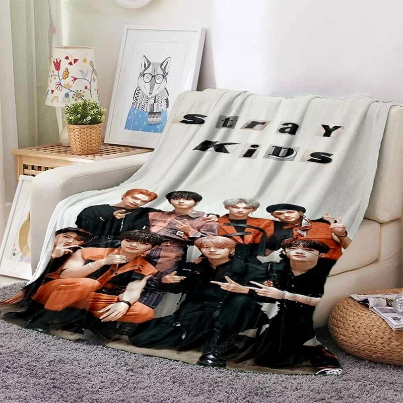 A fleece throw blanket featuring a 3D print of the Stray Kids Kpop group members in dark and orange outfits.