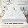 White quilted waterproof mattress cover displayed on a bed, with instructions for use.