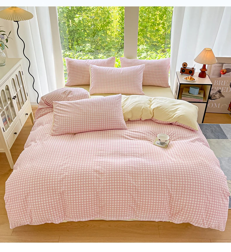 A pink checkered duvet cover set is displayed on a bed in a bright room with white curtains and natural light.