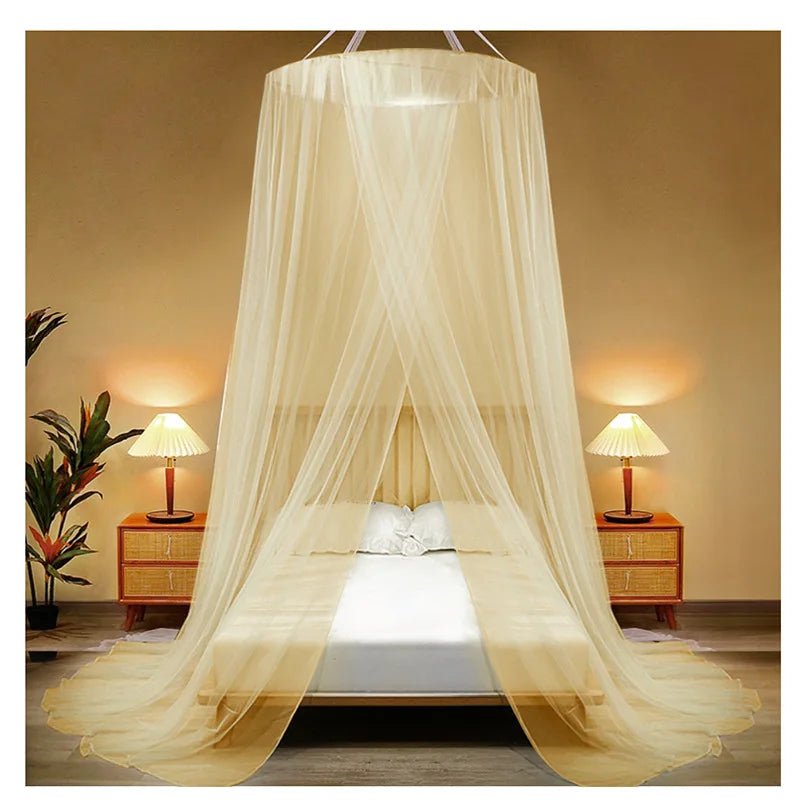 A sheer beige mosquito net canopy draped over a bed, illuminated by bedside lamps.