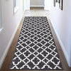 A modern geometric area rug featuring a black and white diamond pattern placed in a hallway.