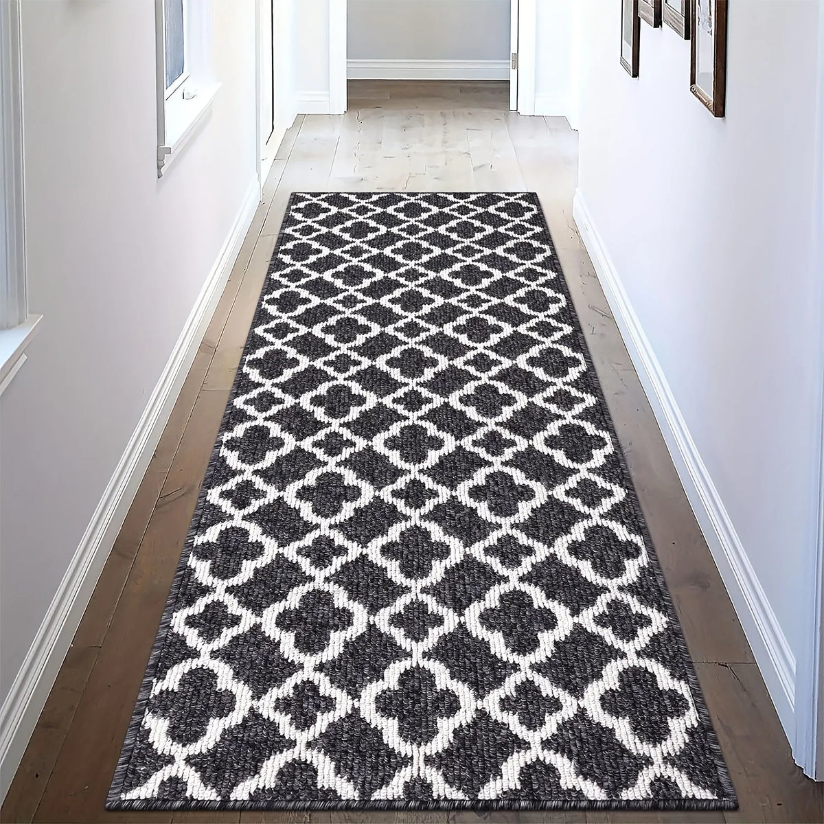 A modern geometric area rug featuring a black and white diamond pattern placed in a hallway.