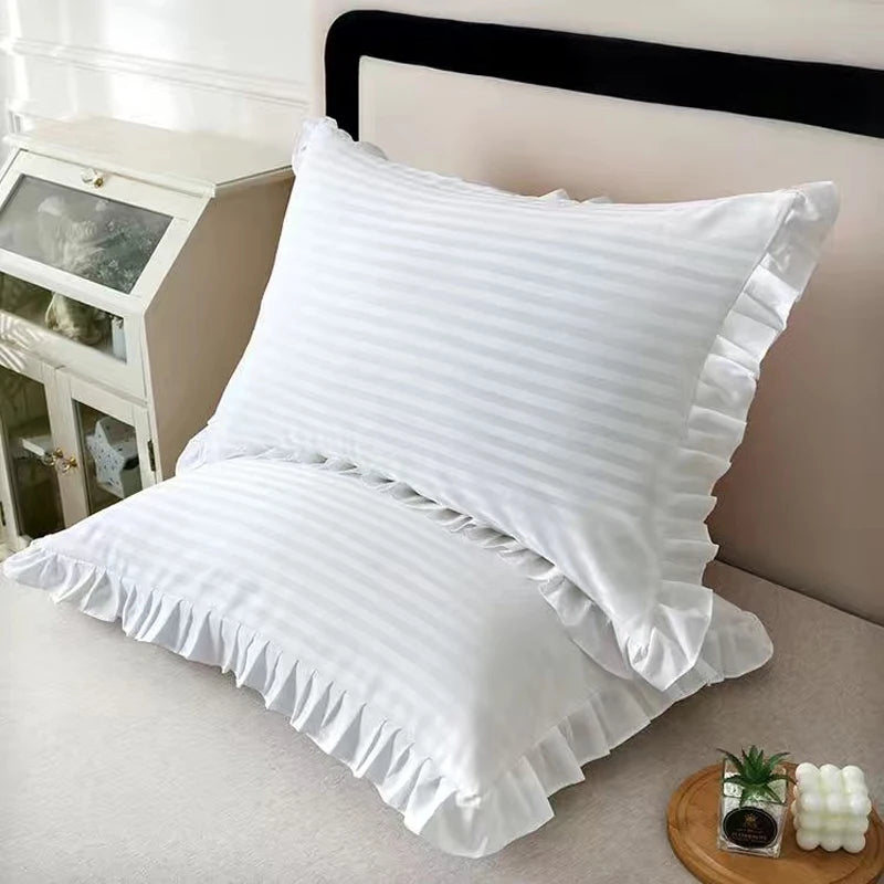 A set of two white minimalist ruffle pillow covers displayed on a bed.