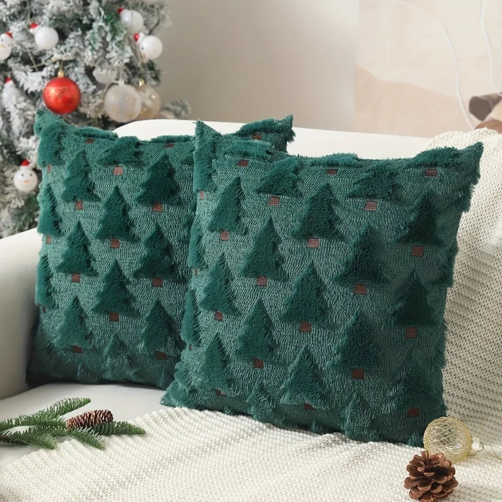 Two dark green textured plush throw pillows shaped like Christmas trees on a white surface.