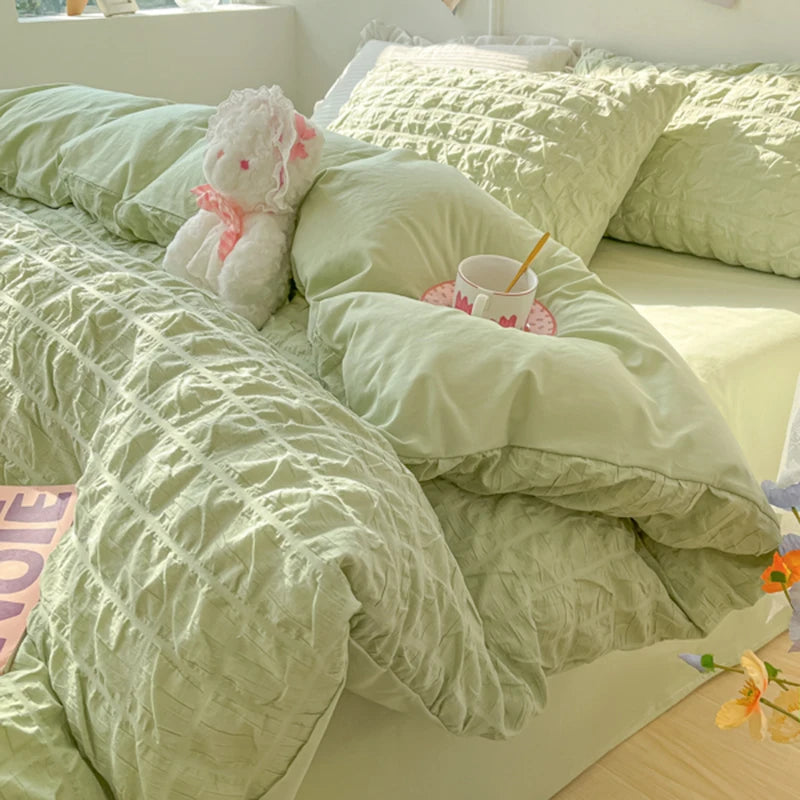 A light green textured duvet cover set with a fluffy pink stuffed animal on a bed.