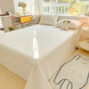 A white organic cotton bedding set with a flat sheet and pillowcases is displayed on a bed in a bright room.