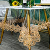 Gold lace embroidered PVC tablecloth draped over a glass table.