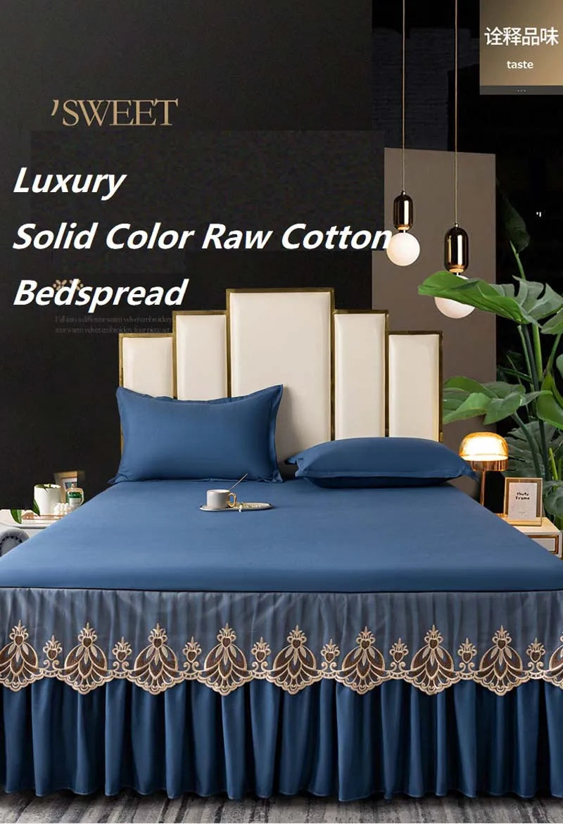 A luxurious navy blue solid color raw cotton bedspread and pillows with gold embroidery on a bed.
