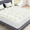 A white quilted viscose bamboo mattress topper placed on a gray bed frame.