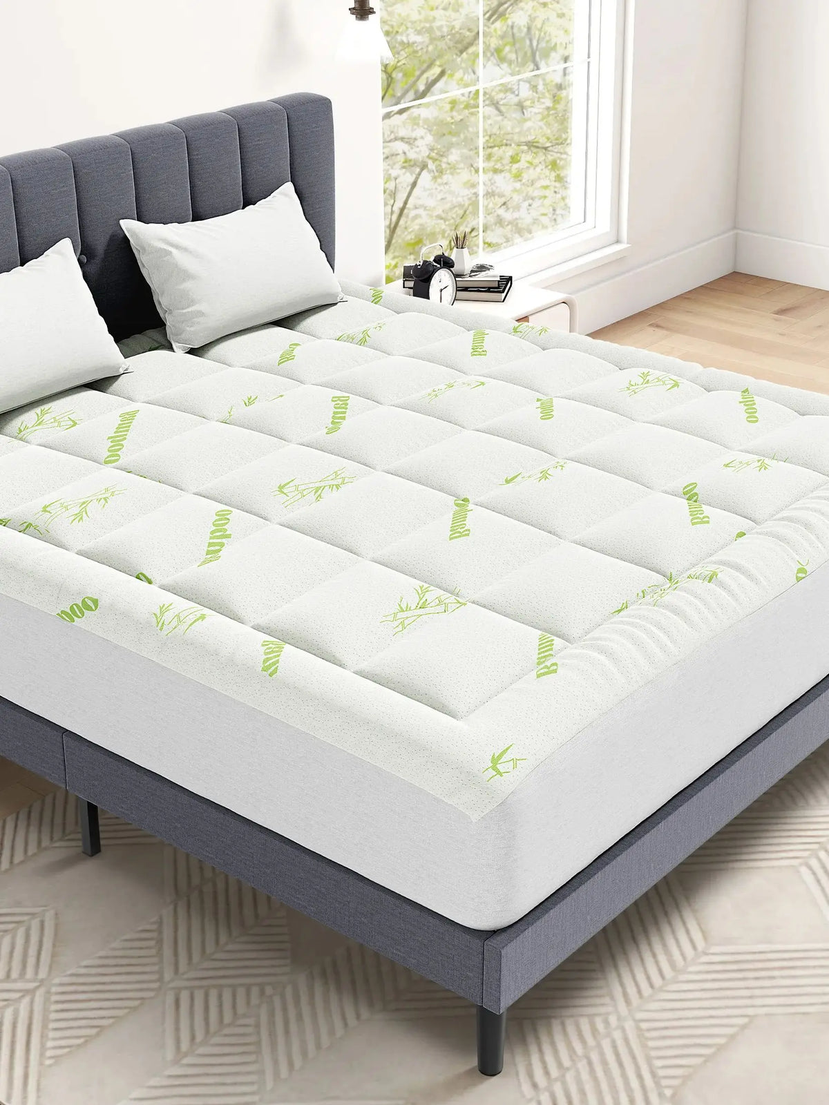 A white quilted viscose bamboo mattress topper placed on a gray bed frame.