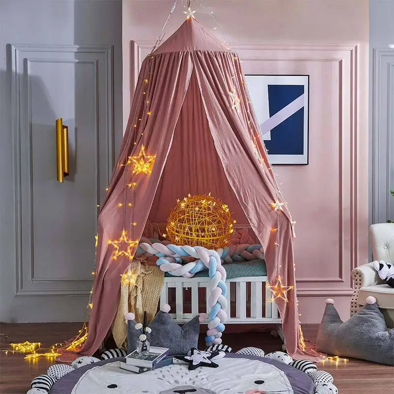 A pink princess hanging bed canopy decorated with gold stars and fairy lights in a bedroom setting.