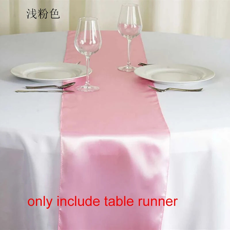 Pink satin table runner set with wine glasses and plates on a white tablecloth