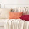A sofa decorated with various textured throw pillows in shades of pink, beige, and terracotta.