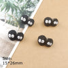 A set of small, black resin ladybug charms with silver accents displayed on brown paper.