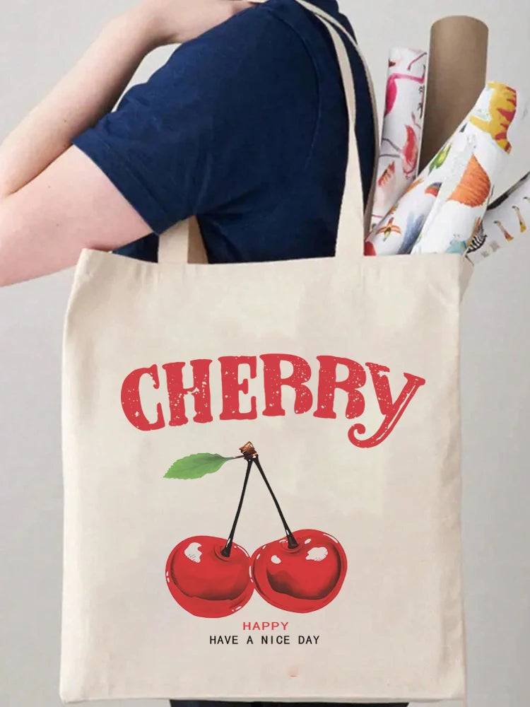 A beige canvas shopping bag featuring the word CHERRY and a graphic of a red cherry with the text HAPPY HAVE A NICE DAY.