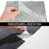 A hand is peeling a clear self-adhesive square carpet tile from a gray carpet surface.