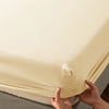 A close-up of a beige soft touch microfiber fitted sheet being held, showing the fabric texture and elastic edge.