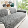 A gray quilted sofa cushion with a diamond pattern displayed on a white sofa.