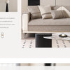 A beige linen sofa with textured throw pillows and a black cylindrical side table in a modern living room setting.