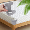 A hand is demonstrating invisible corner tightener clips for a mattress, showing the clip being placed on the fabric.